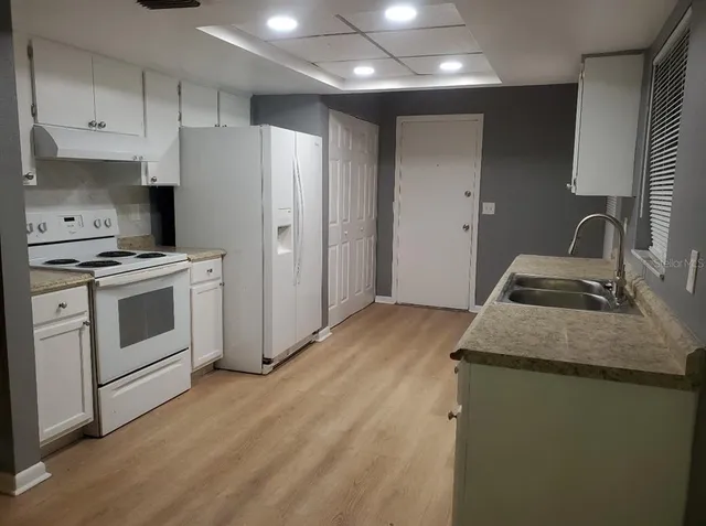 a kitchen with granite countertop a sink stove and refrigerator