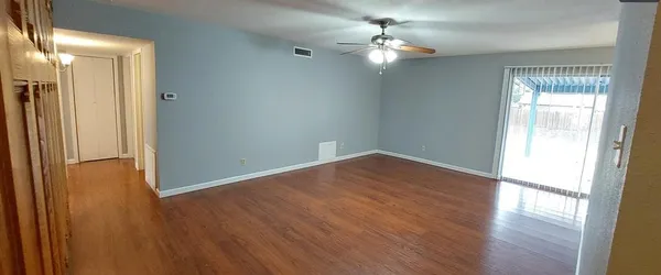 an empty room with wooden floor and windows