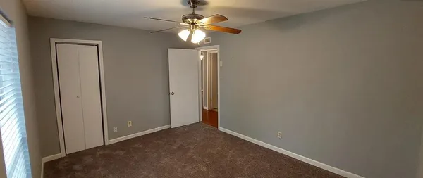 an empty room with a chandelier fan and a window