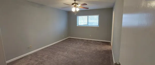 an empty room with a window and a fan