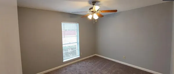 an empty room with windows and fan