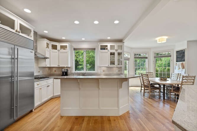 343 Bay Road Hamilton, MA 01982 - Photo 14 of 34 a kitchen with stainless steel appliances granite countertop a stove top oven a sink dishwasher a dining table and chairs with wooden floor