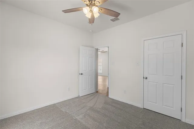 an empty room with closet and a chandelier fan