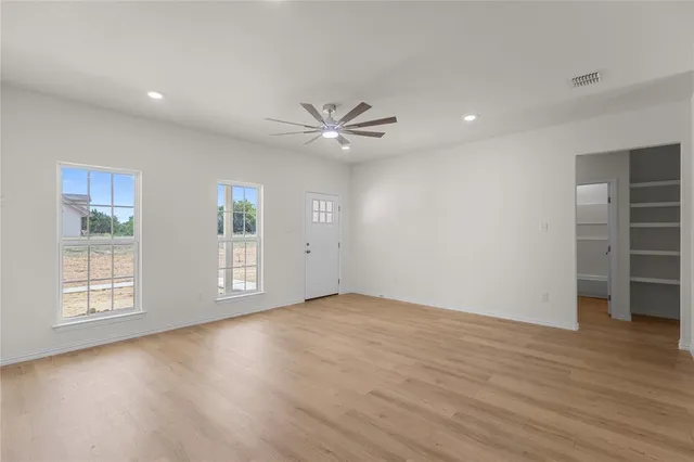 a view of an empty room with a window and wooden floor