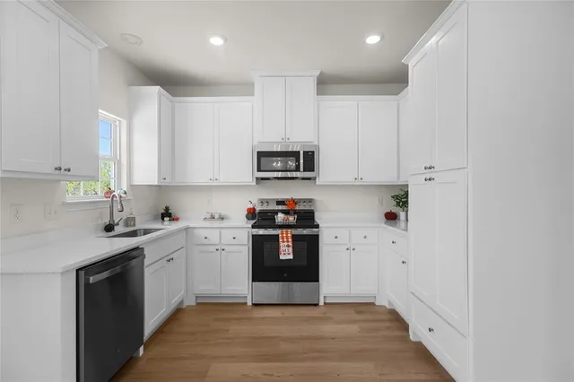 a kitchen with granite countertop white cabinets and stainless steel appliances