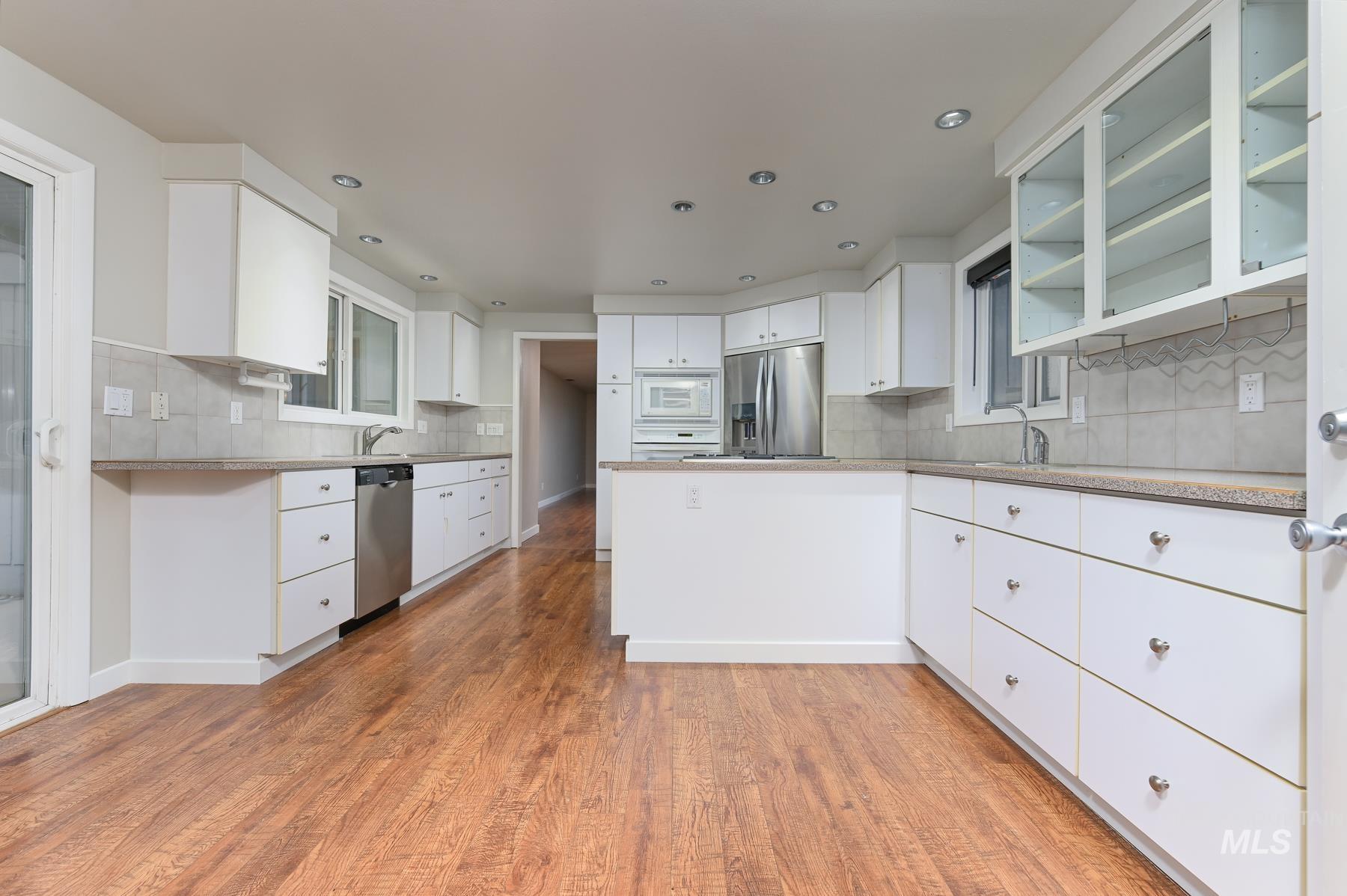 7208 West Cascade Street Boise, ID 83704 - Photo 1 of 49 Kitchen featuring open shelves, white cabinets, light wood-style flooring, backsplash, and a peninsula