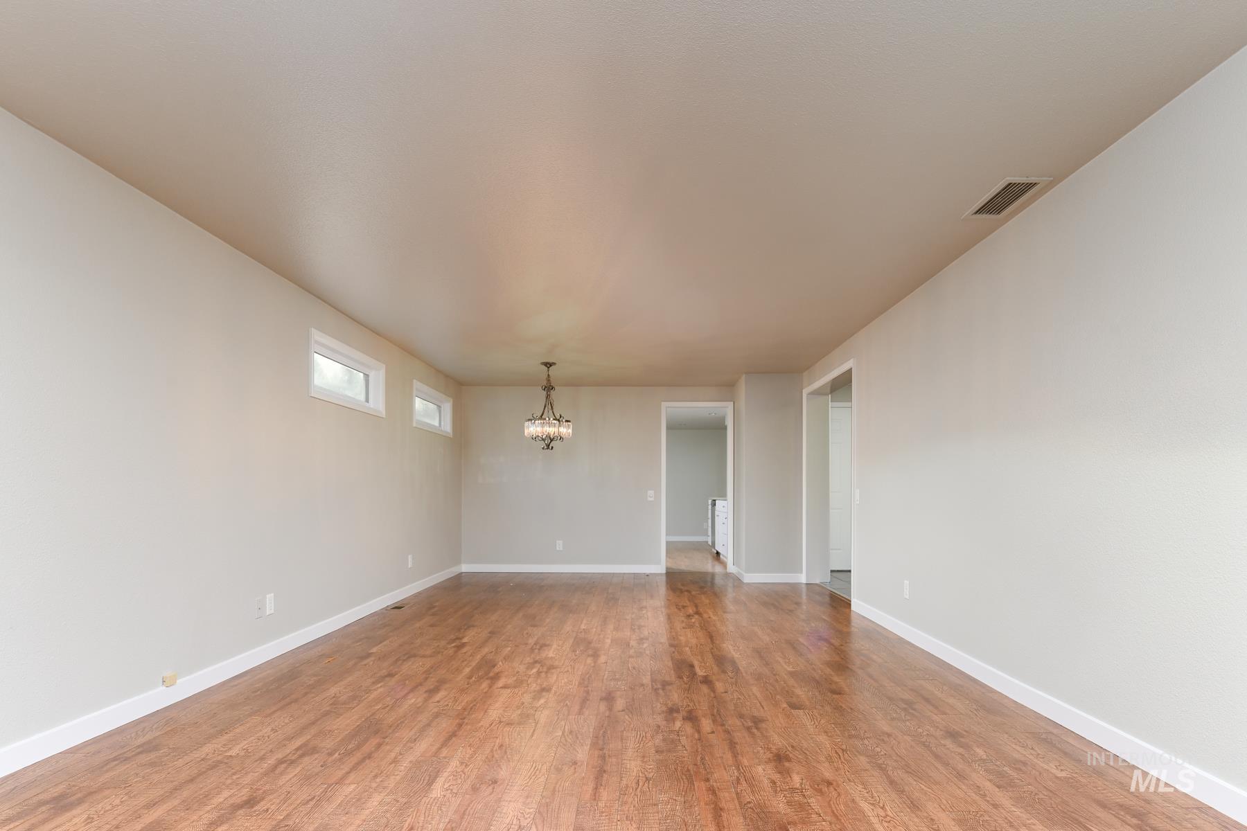 7208 West Cascade Street Boise, ID 83704 - Photo 13 of 49 Unfurnished room featuring wood finished floors and a chandelier