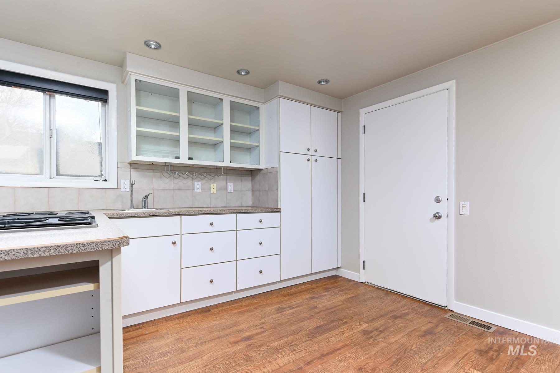 7208 West Cascade Street Boise, ID 83704 - Photo 4 of 49 Kitchen with white cabinetry, tasteful backsplash, light wood-type flooring, and glass insert cabinets