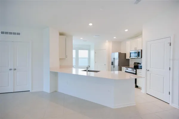a large white kitchen with kitchen island a refrigerator a sink and a stove