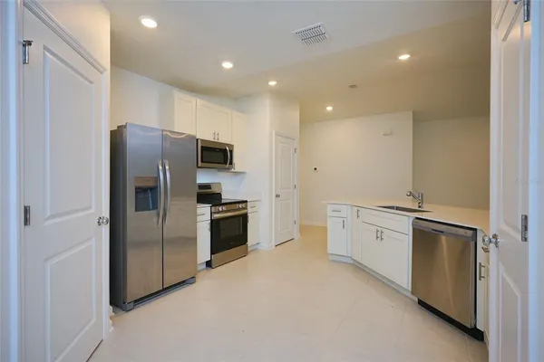 a kitchen with stainless steel appliances granite countertop a refrigerator a sink a stove and a refrigerator with wooden floor