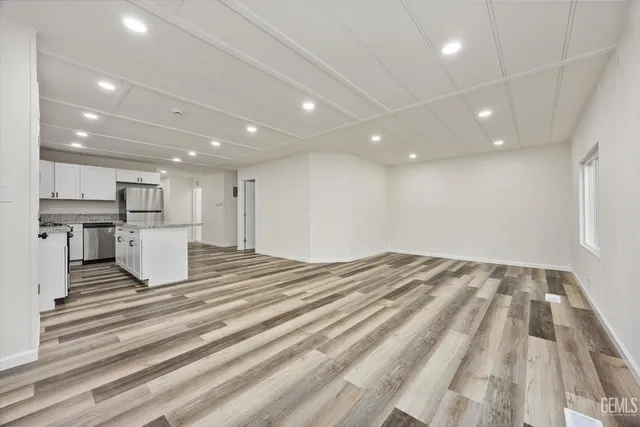 a view of kitchen and empty room with wooden floor