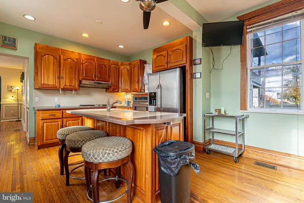 a kitchen with stainless steel appliances granite countertop a table chairs in it and a wooden floors