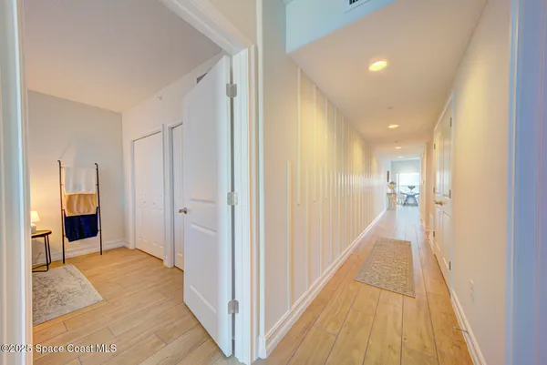 a view of a hallway with wooden floor and a bathroom
