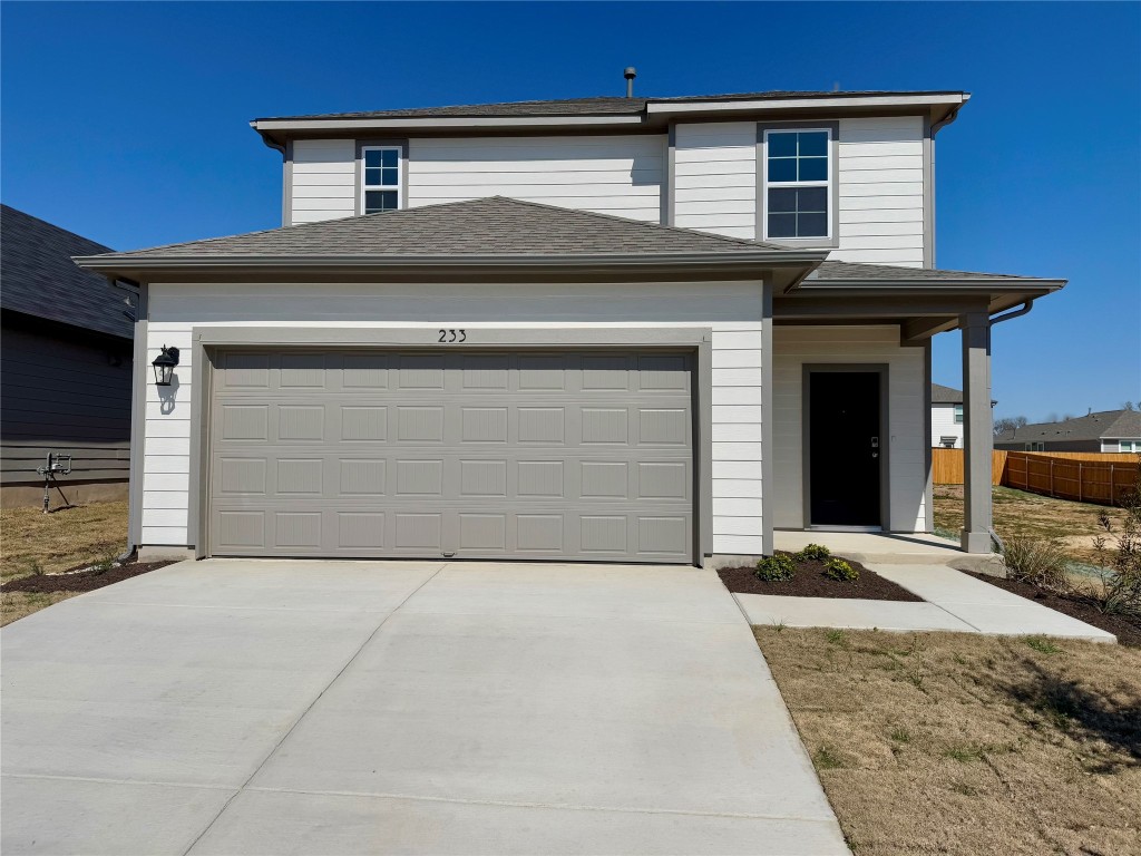 233 Hidalgo Lane Elgin, TX 78621 - Photo 1 of 1 Traditional home with concrete driveway, an attached garage, fence, and a shingled roof