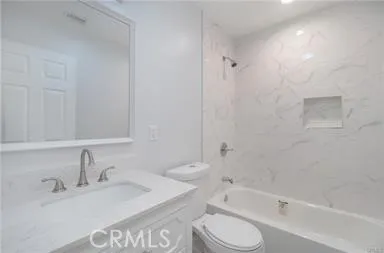 a bathroom with a bathtub shower sink vanity and toilet