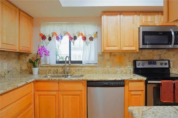 a kitchen with granite countertop stainless steel appliances a stove sink and microwave