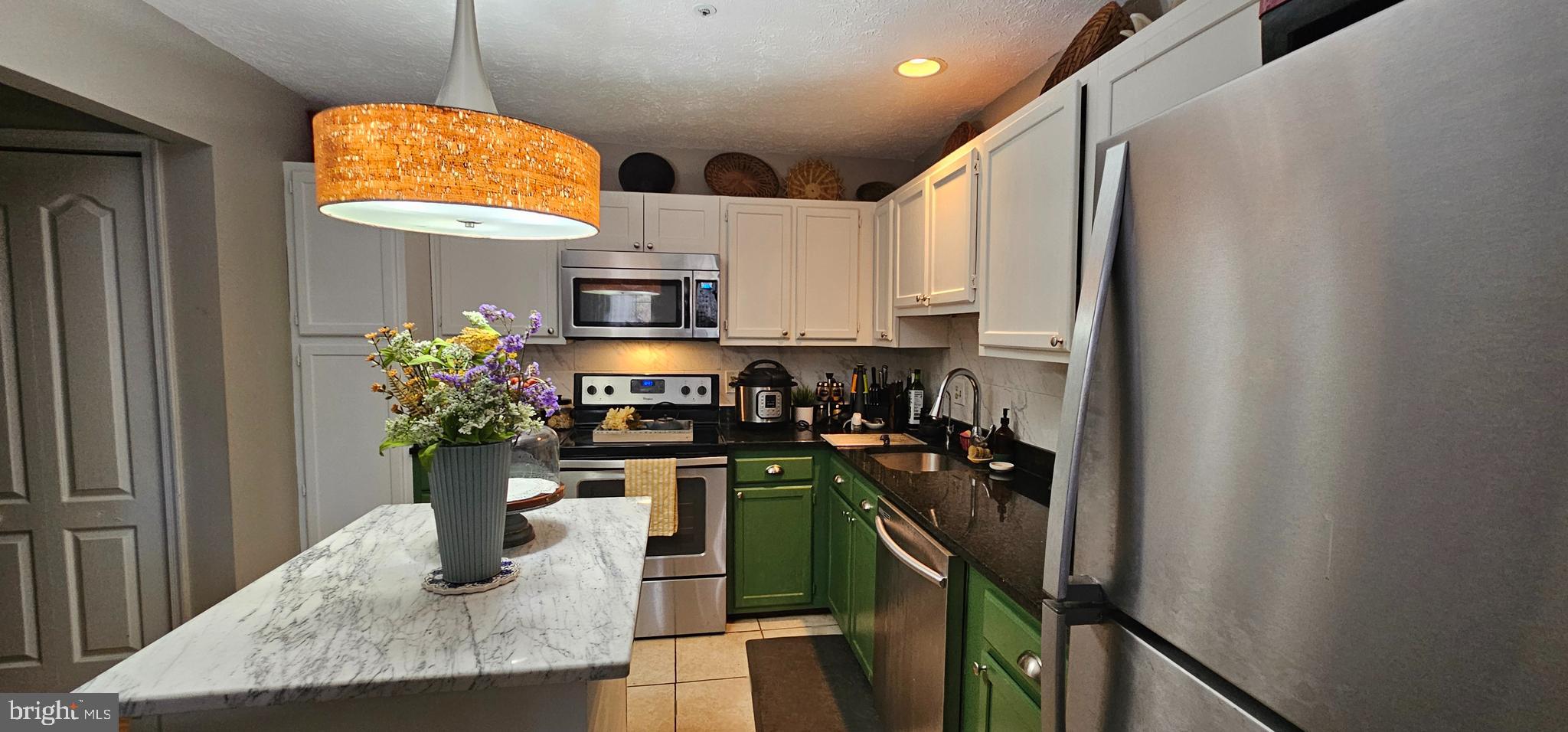 4657 Deepwood Court, Unit 106A Bowie, MD 20720 - Photo 9 of 29 a kitchen with stainless steel appliances granite countertop a sink dishwasher a microwave oven and a dining table with wooden floor