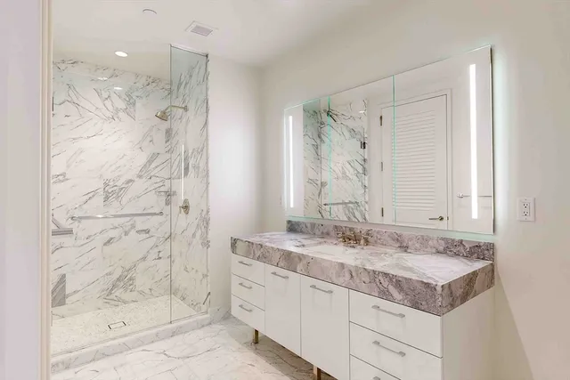 a bathroom with a granite countertop sink mirror and shower