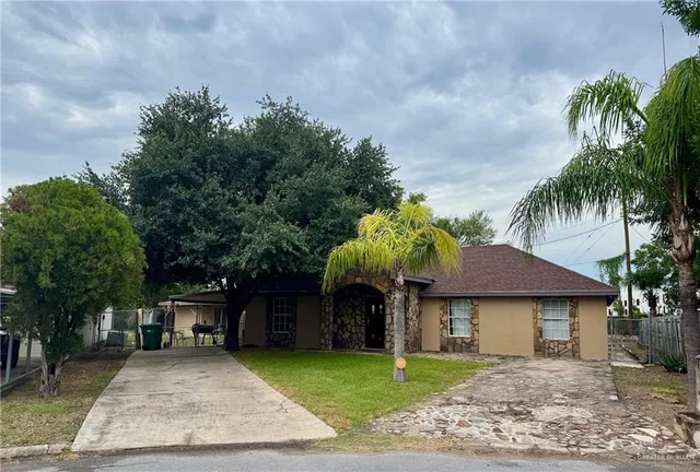 a front view of a house with a garden and tree