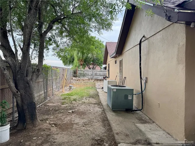 a view of a backyard with large trees and wooden fence