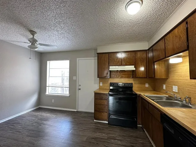 a kitchen with kitchen island granite countertop a sink cabinets and stainless steel appliances