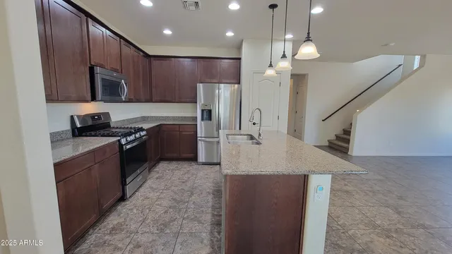 a kitchen with stainless steel appliances granite countertop a sink a stove and a refrigerator
