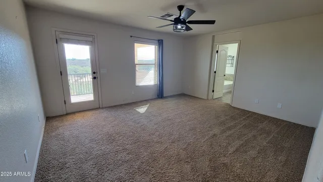 a view of a big room with windows and chandelier fan