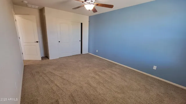 an empty room with a fan and a chandelier fan