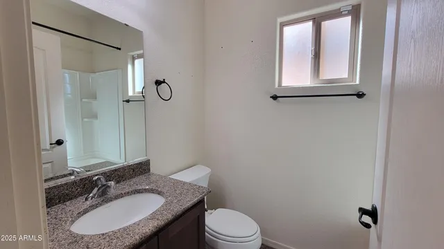 a bathroom with a granite countertop sink toilet a mirror and shower