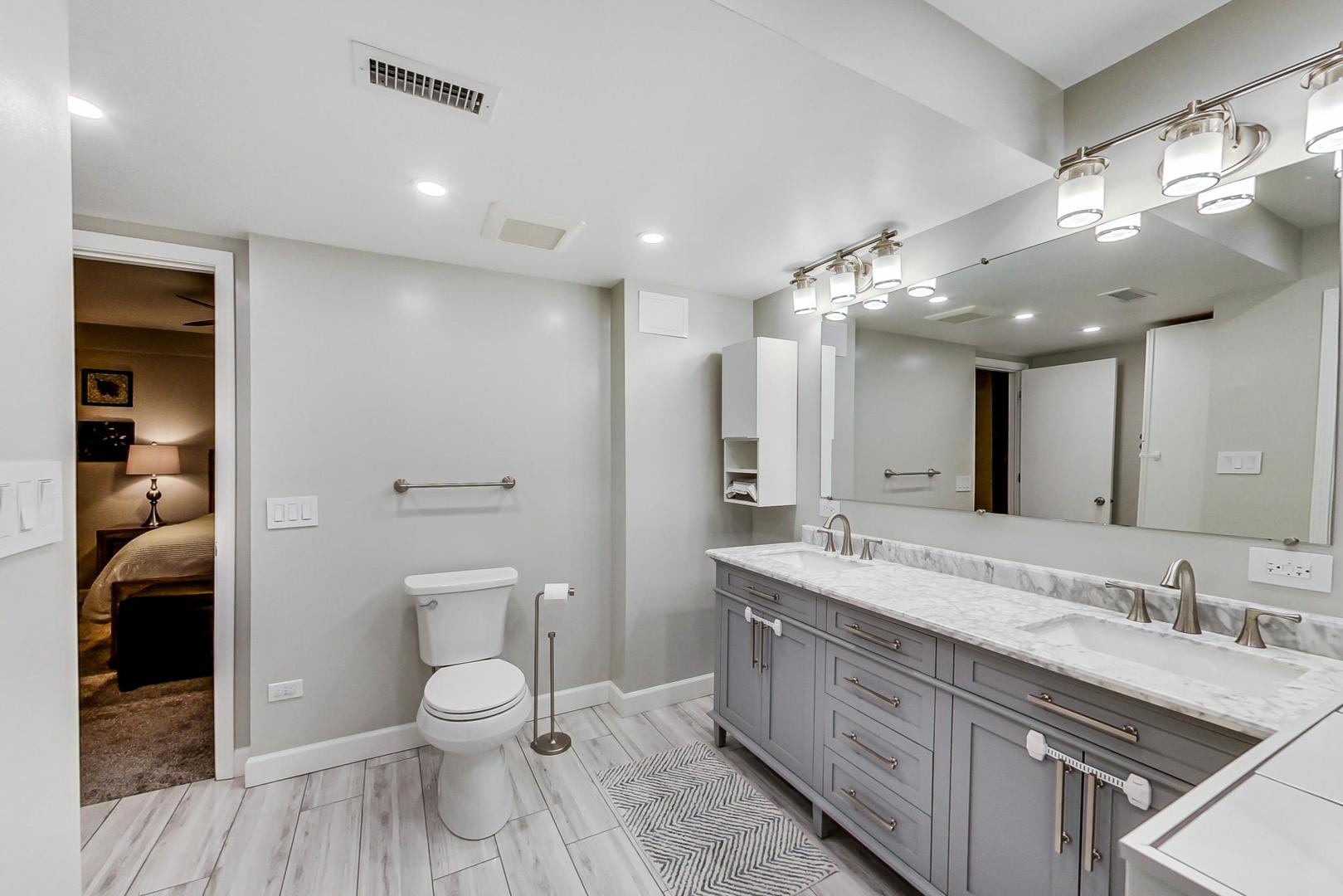 1532 West Fry Street, Unit 1 Chicago, IL 60642 - Photo 25 of 34 a spacious bathroom with a granite countertop toilet a sink and a large mirror