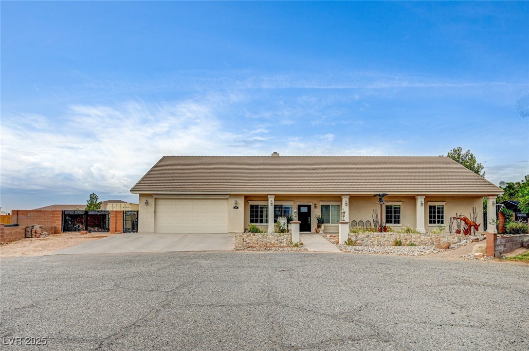 Ranch-style house featuring stucco siding, a porch, driveway, and a gate