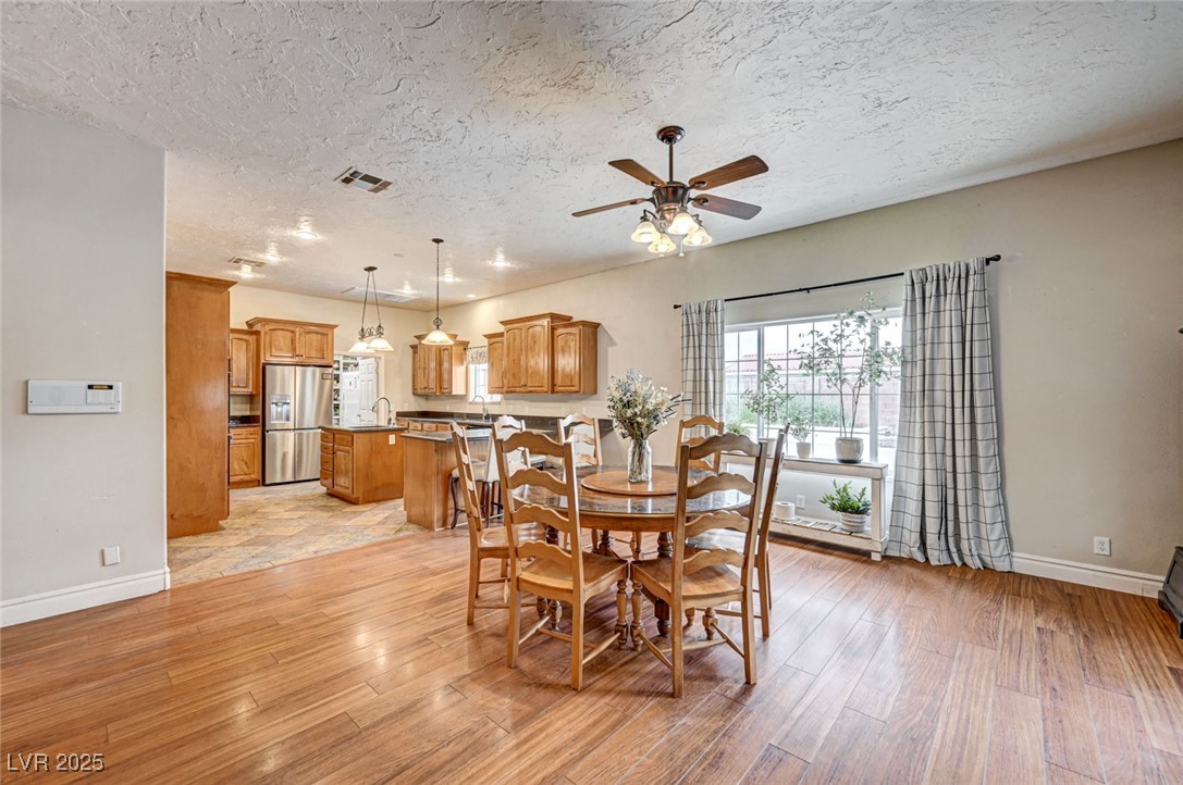 1140 Mahoney Avenue Logandale, NV 89021 - Photo 18 of 51 Dining space featuring ceiling fan, light wood-style floors, and a textured ceiling
