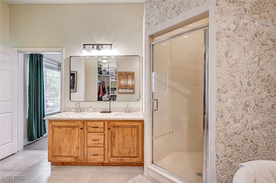 1140 Mahoney Avenue Logandale, NV 89021 - Photo 28 of 51 Bathroom featuring double vanity, a shower stall, light tile patterned floors, and a closet