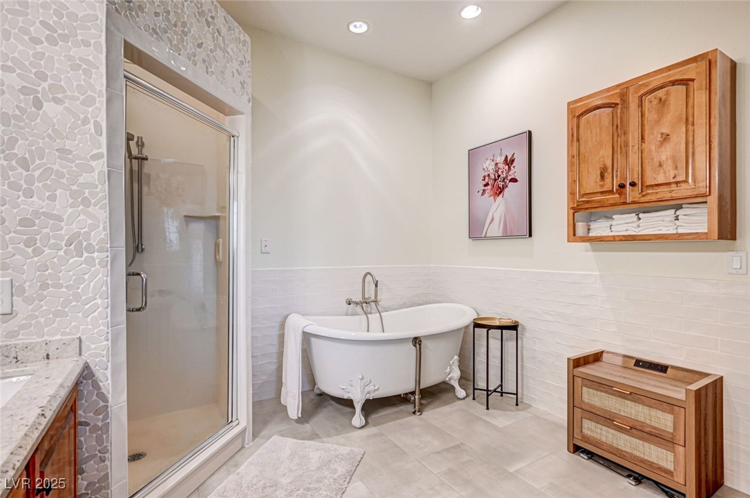 1140 Mahoney Avenue Logandale, NV 89021 - Photo 29 of 51 Full bathroom featuring tile walls, a freestanding tub, recessed lighting, vanity, and a shower stall