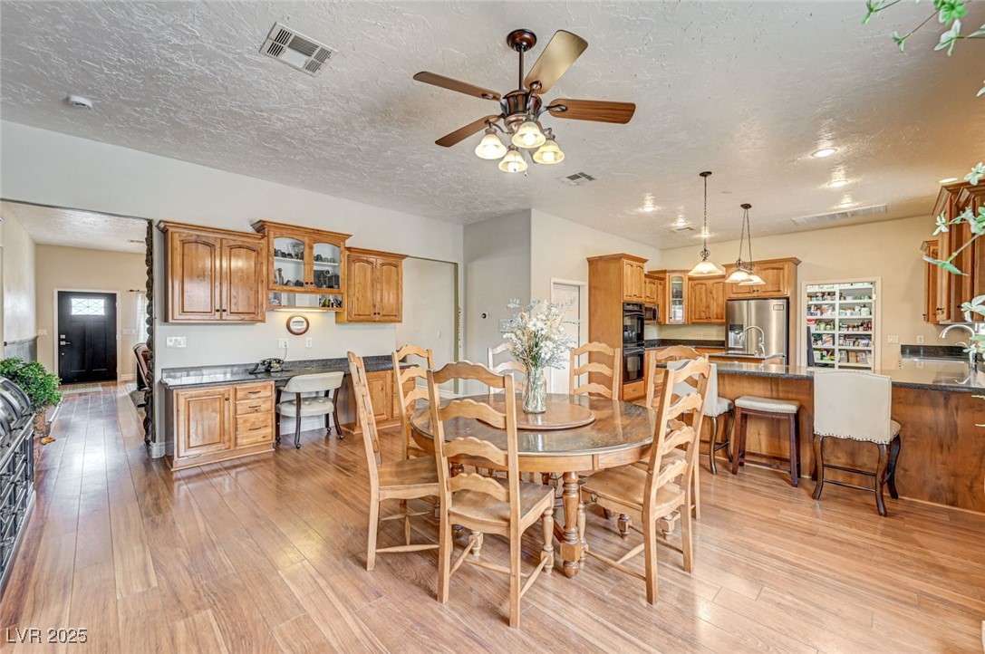 1140 Mahoney Avenue Logandale, NV 89021 - Photo 3 of 51 Dining room with ceiling fan, light wood-style flooring, and a textured ceiling