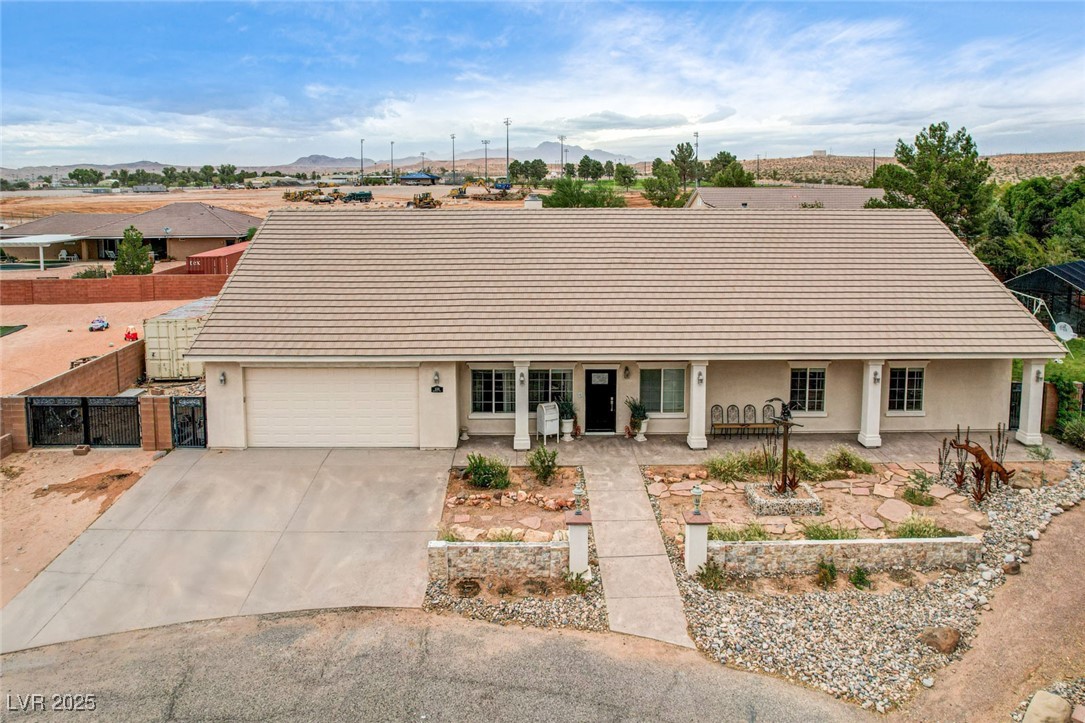 1140 Mahoney Avenue Logandale, NV 89021 - Photo 10 of 51 View of front of house featuring stucco siding, concrete driveway, a mountain view, an attached garage, and a tile roof