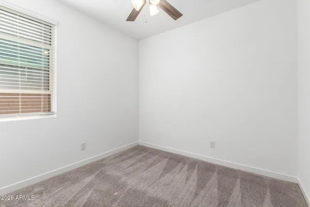 an empty room with a window and a fan