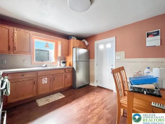 a kitchen with stainless steel appliances granite countertop a refrigerator a sink dishwasher a dining table and chairs with wooden floor