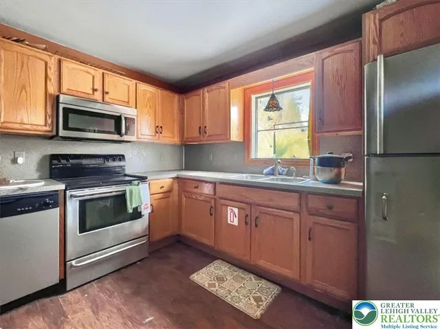 a kitchen with stainless steel appliances granite countertop a stove a sink dishwasher a microwave oven and a refrigerator with wooden cabinets