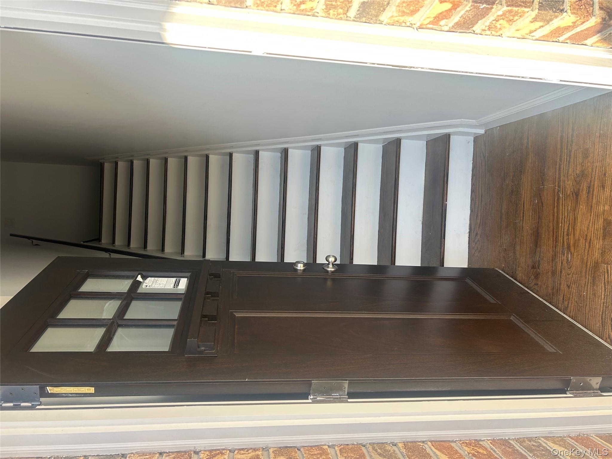 Staircase featuring wood finished floors and brick wall
