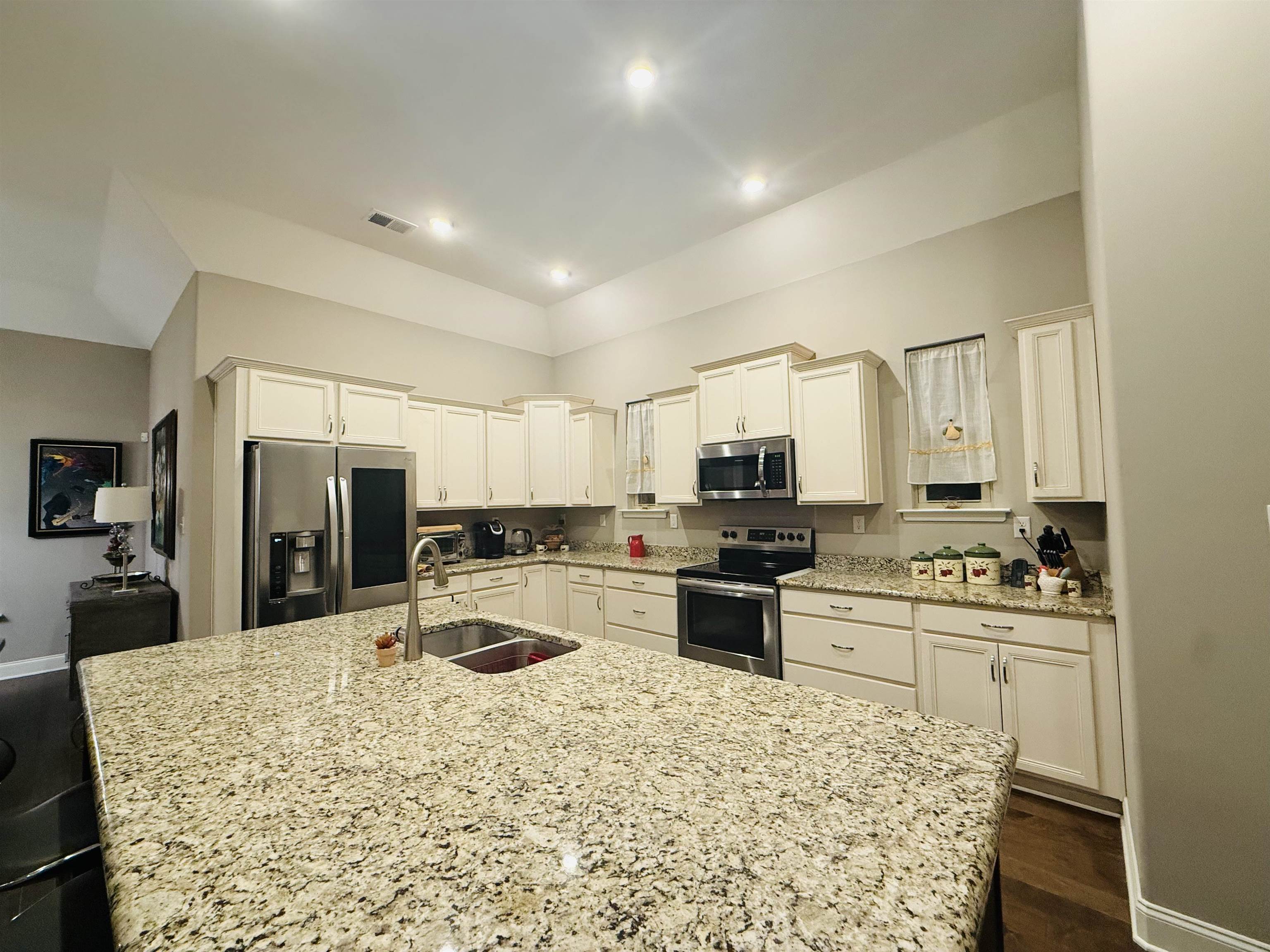 8443 Butterfly View Lane Bartlett, TN 38133 - Photo 11 of 12 Kitchen with stainless steel appliances, light stone countertops, white cabinetry, dark wood-type flooring, and an island with sink