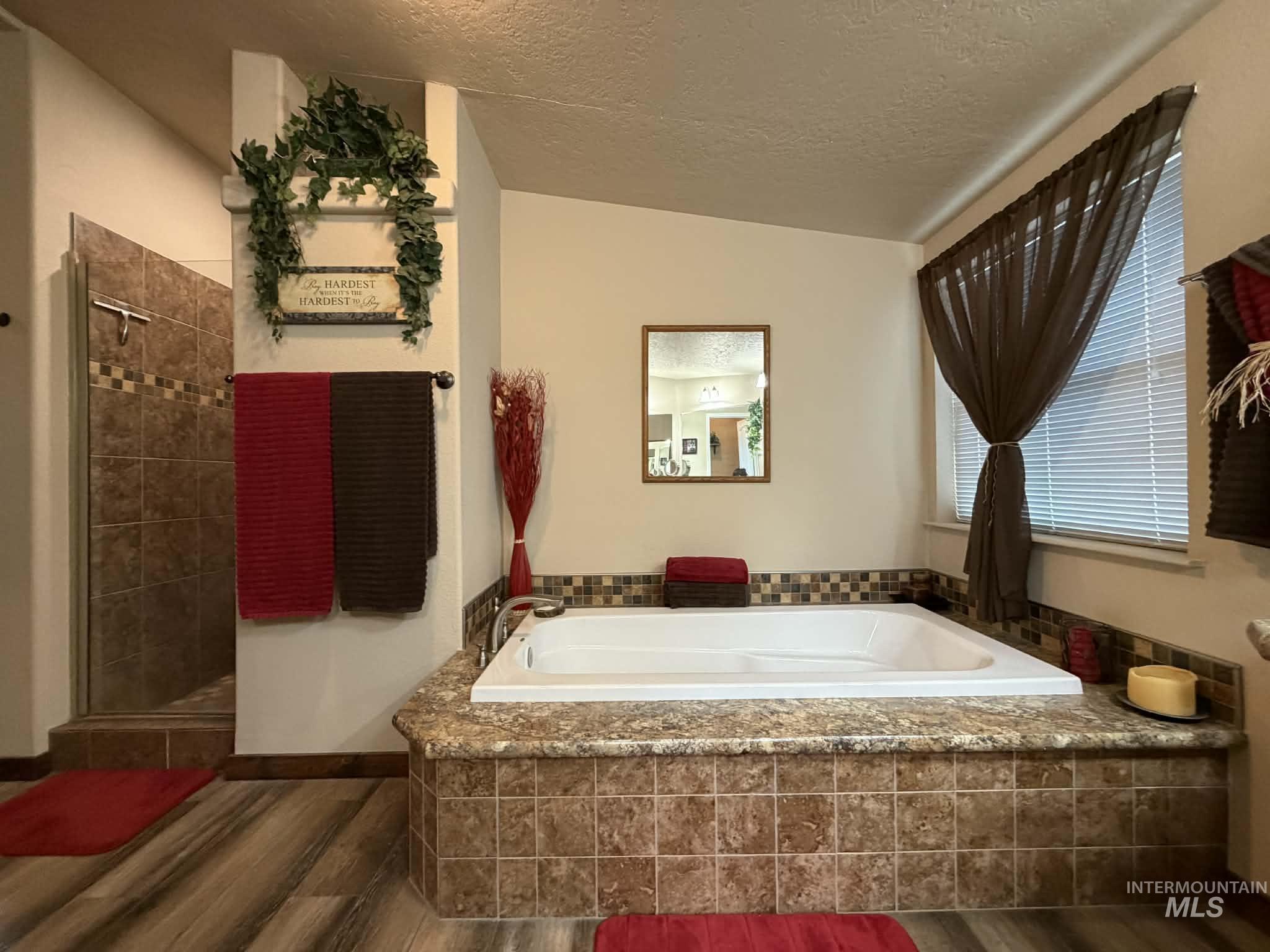 19378 Homestead Loop Lewiston, ID 83501 - Photo 19 of 42 Full bathroom featuring dark wood-type flooring, a stall shower, a bath, and a textured ceiling