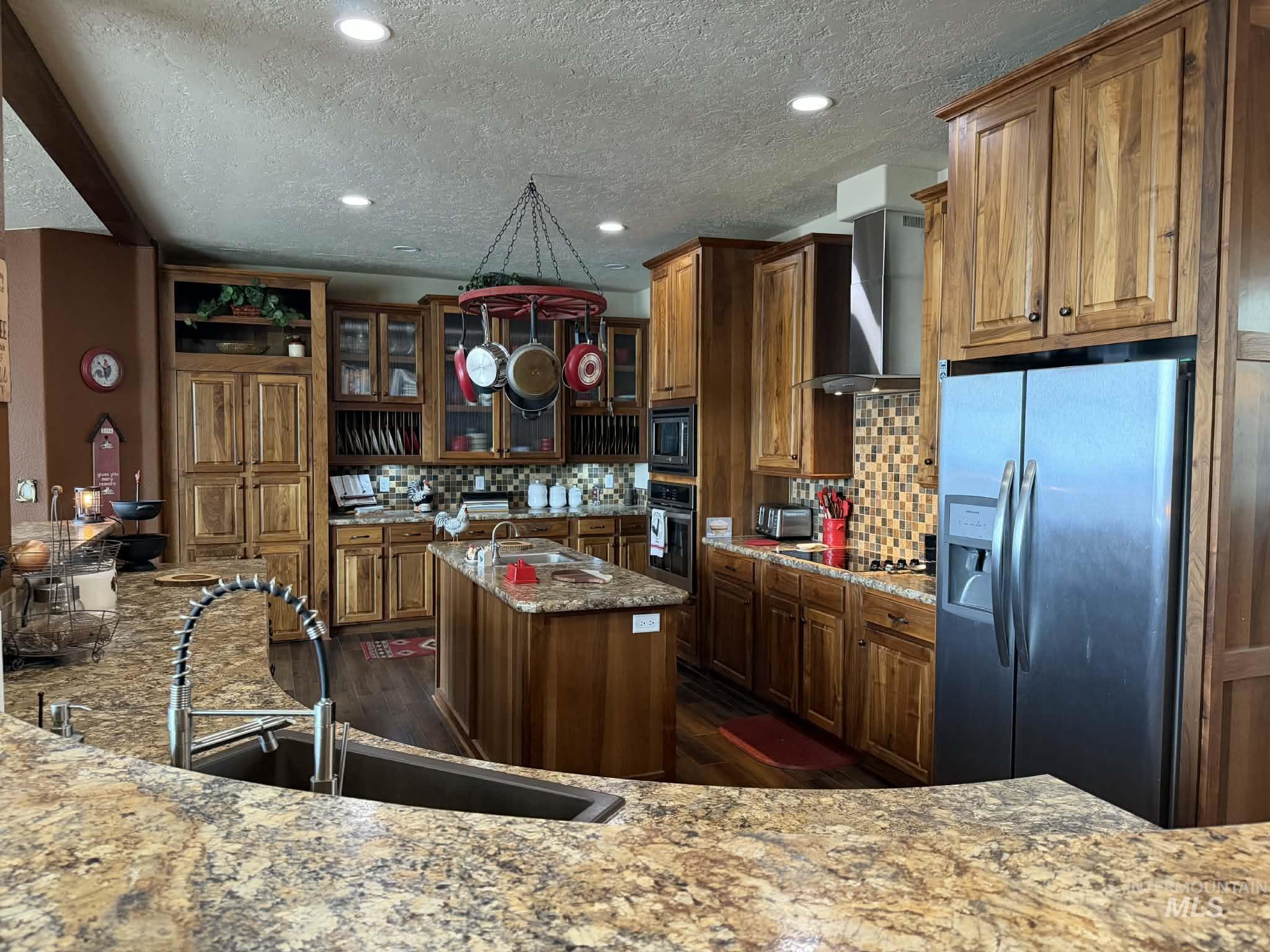 19378 Homestead Loop Lewiston, ID 83501 - Photo 5 of 42 Kitchen featuring appliances with stainless steel finishes, decorative backsplash, glass insert cabinets, light stone counters, and brown cabinetry