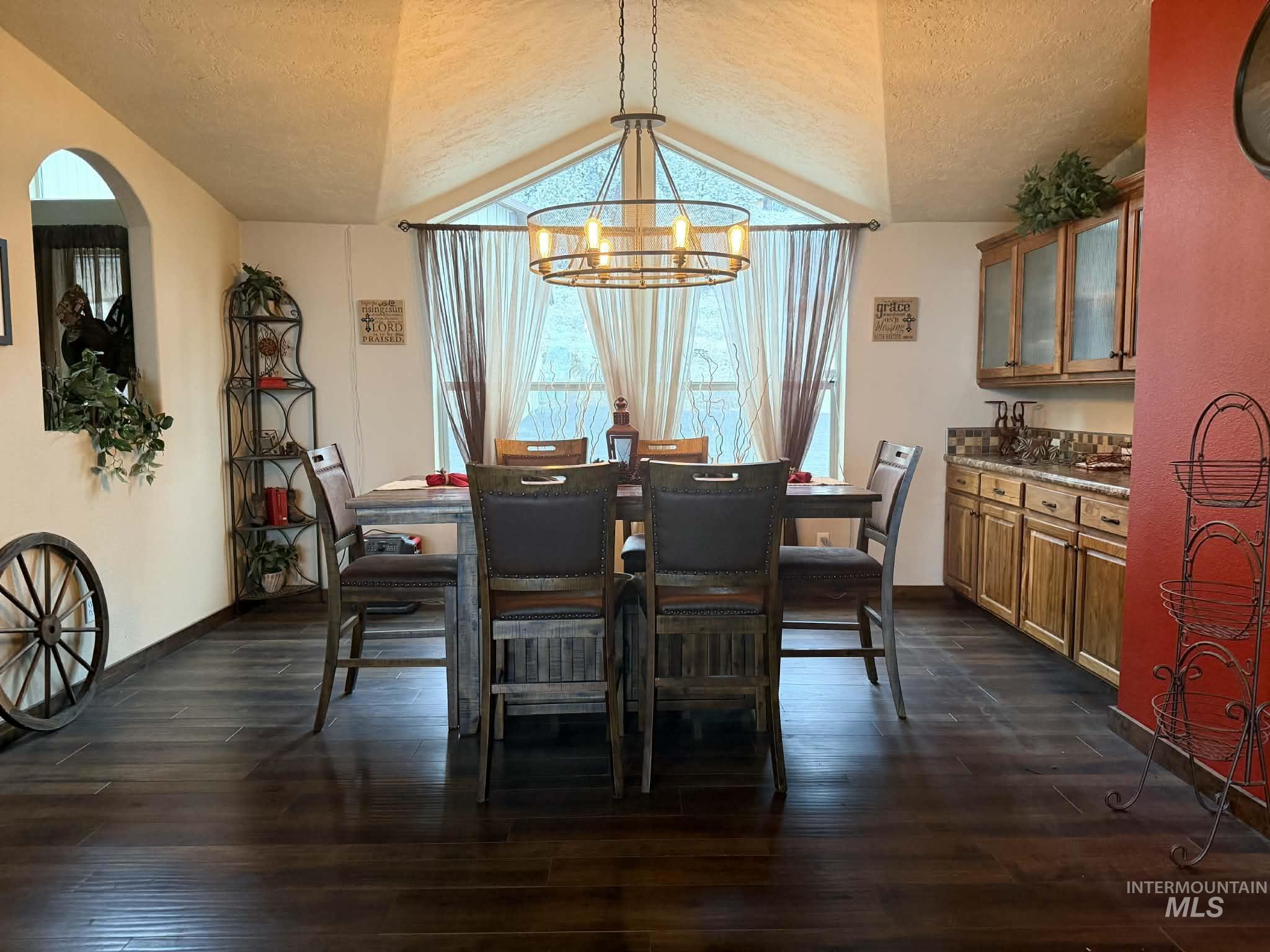 19378 Homestead Loop Lewiston, ID 83501 - Photo 8 of 42 Dining space featuring a textured ceiling, vaulted ceiling, dark wood finished floors, and a chandelier