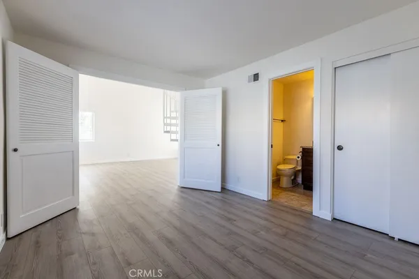 an empty room with wooden floor and closet area