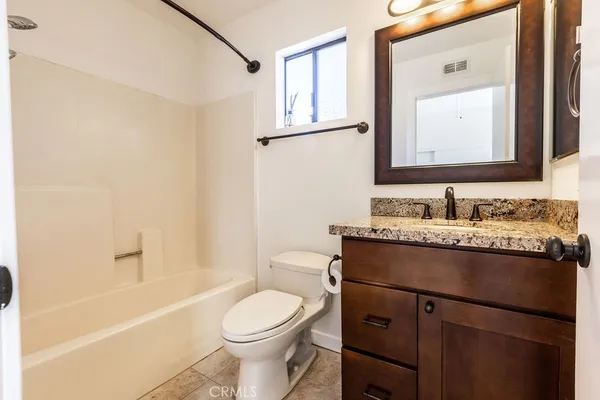 a bathroom with a granite countertop sink toilet mirror and a bathtub
