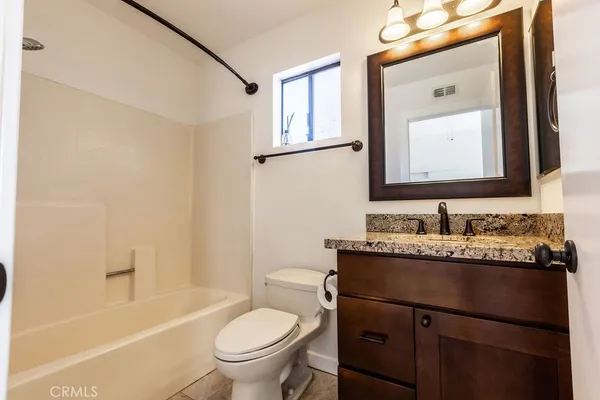 a bathroom with a granite countertop sink mirror toilet and bathtub
