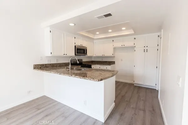 a kitchen with kitchen island granite countertop a sink appliances cabinets and a counter top space