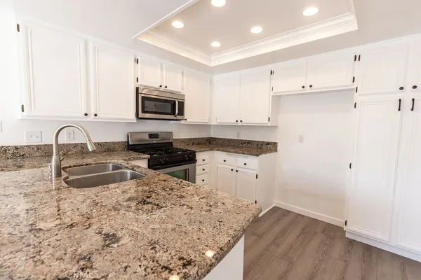a kitchen with granite countertop a sink and a stove top oven with wooden floor