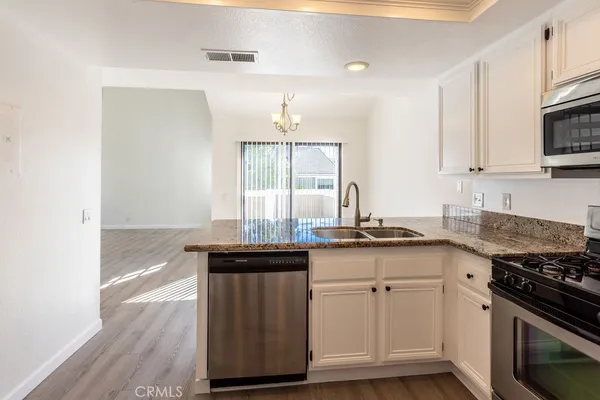 a kitchen with granite countertop a sink cabinets and stainless steel appliances